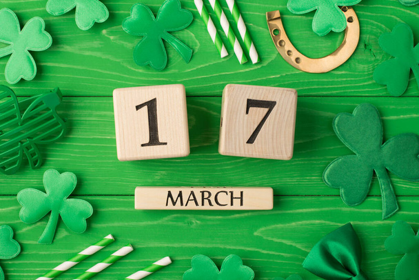Happy St. Patrick's Day. In alto sopra la testa primo piano flatlay vista foto foto di calendario in legno cubo con data e accessori partito isolato colore brillante sfondo verde - Foto, immagini