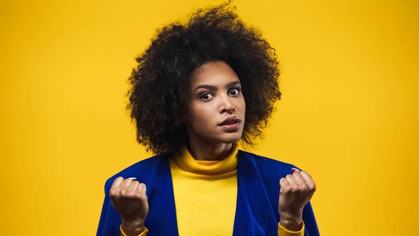 黄色に隔離された拳を示す怒っているアフリカ系アメリカ人女性 - 写真・画像