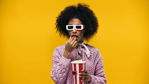 African american woman in 3d glasses eating popcorn isolated on yellow - Photo, Image