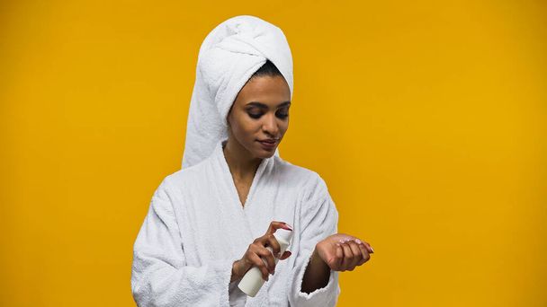 黄色に単離された手に消臭剤を噴霧アフリカ系アメリカ人女性  - 写真・画像