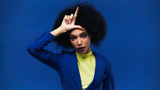 African american woman showing loser sign isolated on blue - Photo, Image