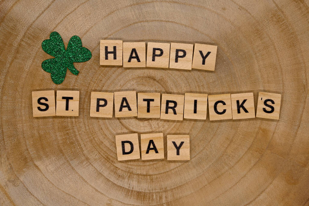 fa betűk, hogy a kifejezés Boldog Szent Patrick nap és zöld lóherék a fa háttér, felülnézet. - Fotó, kép