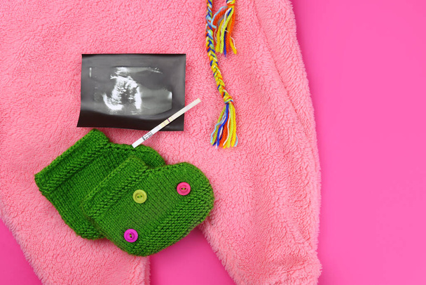 prueba de embarazo positiva, ecografía y ropa de bebé. El concepto de esperar a un niño - Foto, imagen