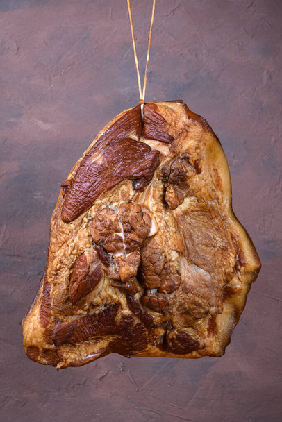 Кусок свежего копченого мяса, подвешенного на веревке - Фото, изображение