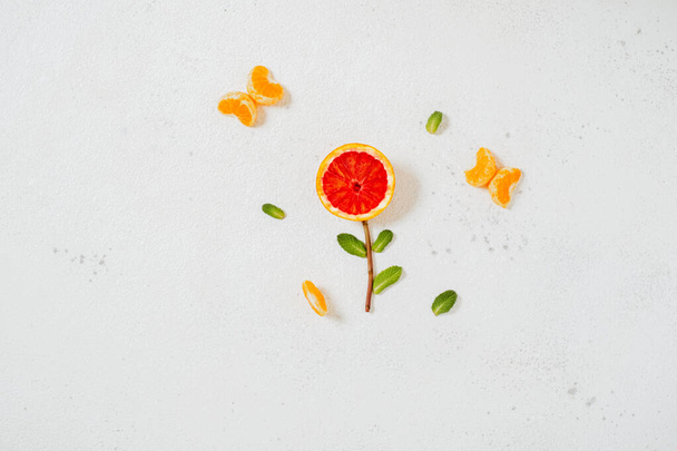 Fleur avec pamplemousse, menthe et tranches de mandarine sur fond blanc. Le concept minimal de printemps, l'alimentation, la légèreté, la bonne humeur. Photo de haute qualité - Photo, image