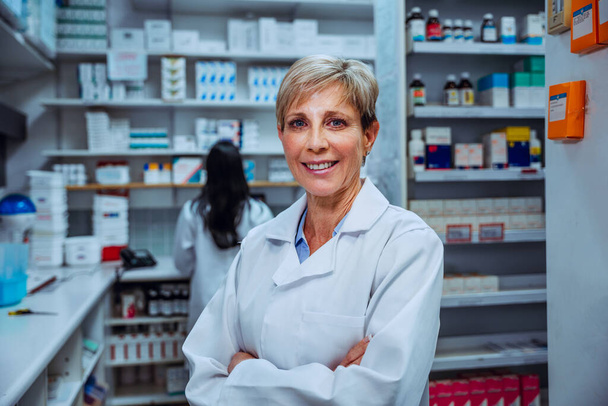 Χαμογελαστή γυναίκα φαρμακοποιός στέκεται με σταυρούς στα φαρμακεία φαρμακείο  - Φωτογραφία, εικόνα