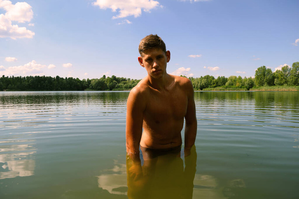 Fiatal meztelen férfi a tavon a vízben derékig. Úszás - Fotó, kép