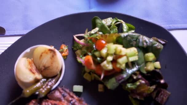 Мясо на гриле, салат, жареный лук и перец чили на тарелке - Кадры, видео