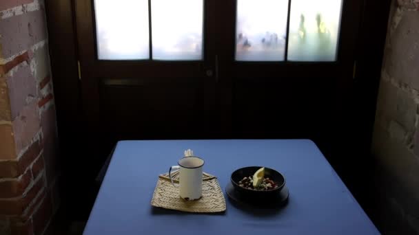 Copo de metal branco e tigela preta na mesa azul - Filmagem, Vídeo