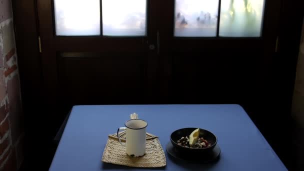 青いテーブルの上に白い金属カップと黒いボウル - 映像、動画