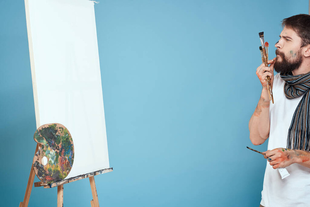 Artista masculino caballete arte dibujo creatividad fondo azul - Foto, Imagen