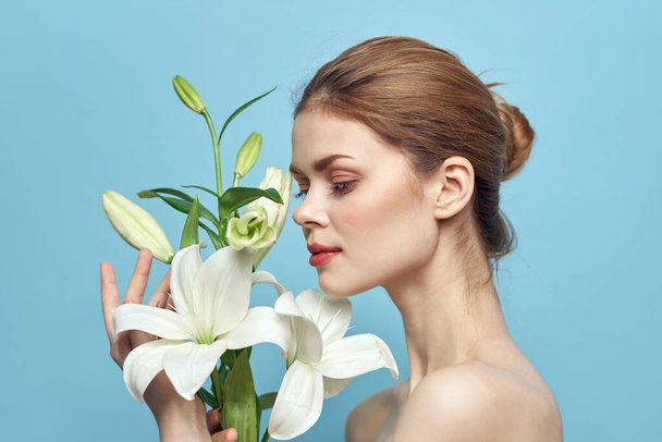 encantadora mulher com flores brancas no fundo azul retrato recortado vista - Foto, Imagem