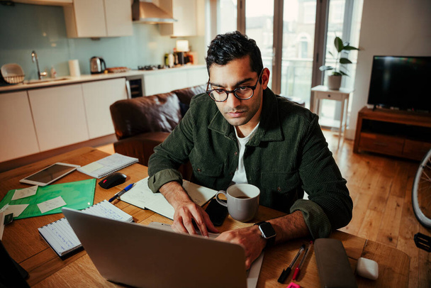 Empresário de corrida mista trabalhando em laptop sentado no escritório em casa  - Foto, Imagem