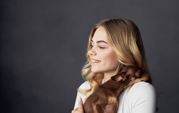 rubia sosteniendo un pequeño perro mascota amistad de cerca - Foto, imagen