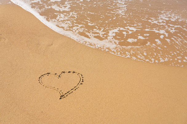 Herz auf den Sand am Strand gemalt und Schaum aus den Wellen. Valentinstag-Konzept. - Foto, Bild