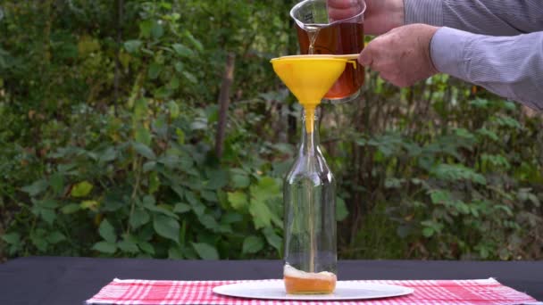 Verser du vinaigre de cidre de pomme naturel dans des bouteilles en verre stériles (Acetum) - Séquence, vidéo