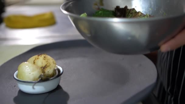 Pinze che aggiungono fette di pomodoro arrosto e nopal a un piatto nero - Filmati, video