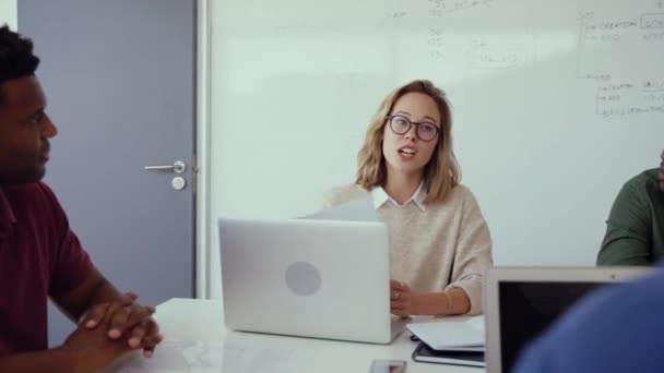 Female designer chatting to mixed race colleagues researching on laptop working on collaboration project during morning meeting in office  - Footage, Video
