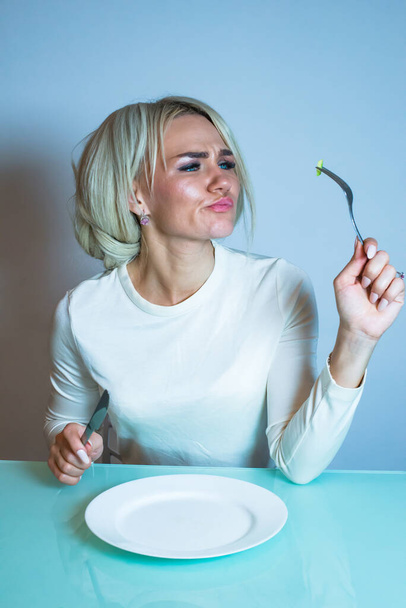Sick girl sits at the table and eats a vegetable. - Fotó, kép