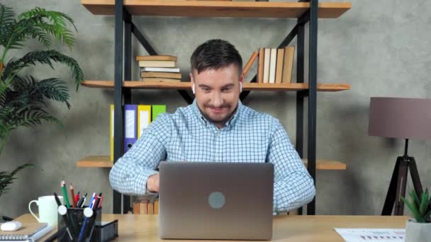 Sonriente profesor hombre sentado en la silla en el escritorio en casa abierto y empezar a usar el ordenador portátil - Metraje, vídeo