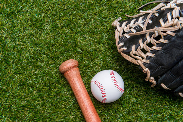Baseball bat, glove and ball on green grass field.  Sport theme background with copy space for text and advertisment - Photo, Image