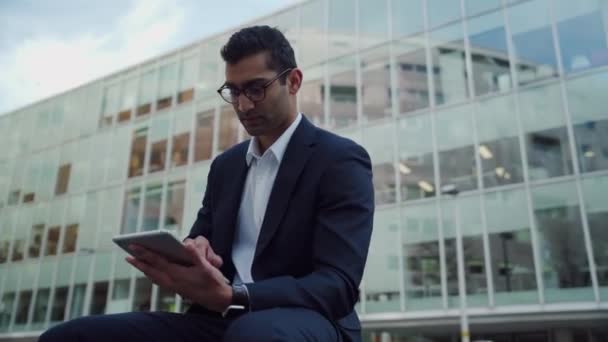 Gemischter Geschäftsmann lächelt und tippt auf digitalem Tablet auf Dachbalkon über Arbeitsbüro  - Filmmaterial, Video
