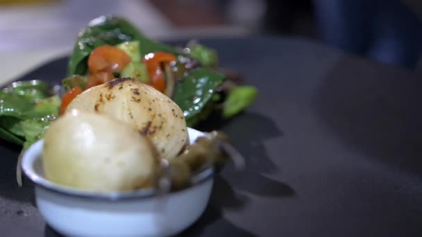 Kleště přidávající pečené rajče a nopálové plátky na černý talíř - Záběry, video