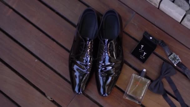 Zapatos para hombre lacados, reloj de pulsera, perfume, gemelos, pajarita sobre fondo de madera - Metraje, vídeo