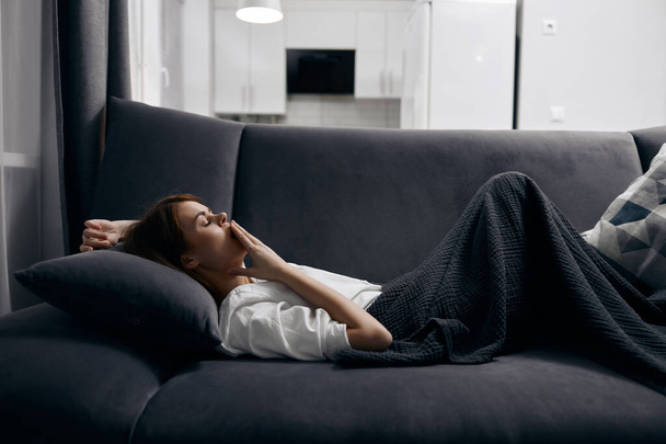 mulher em t-shirt branca está descansando deitado no sofá dentro de casa - Foto, Imagem