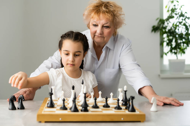 Grandmother and young girl playing chess together at home - Photo, Image