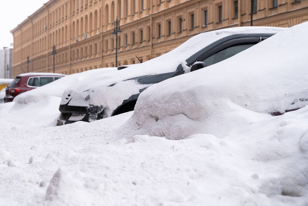 Pysäköityjä autoja lumen peitossa lumisella tiellä lumisateen jälkeen. Huono talvi sää.  - Valokuva, kuva