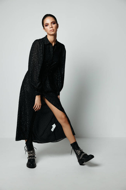 nő fekete ruhában csupasz láb divat fekete csizma - Fotó, kép