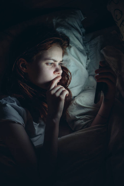 mujer se encuentra en la cama antes de acostarse con el teléfono en las manos comunicación estilo de vida ocio - Foto, imagen