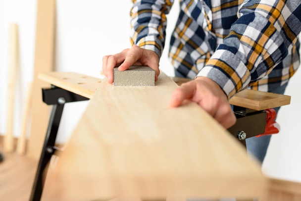 Primer plano de una mujer en casa lijando una madera en un banco de trabajo. Foto de alta calidad. - Foto, imagen