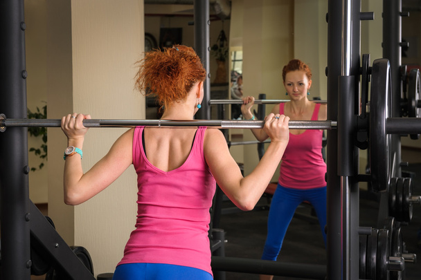 young girl doing squats with barbell - Photo, Image