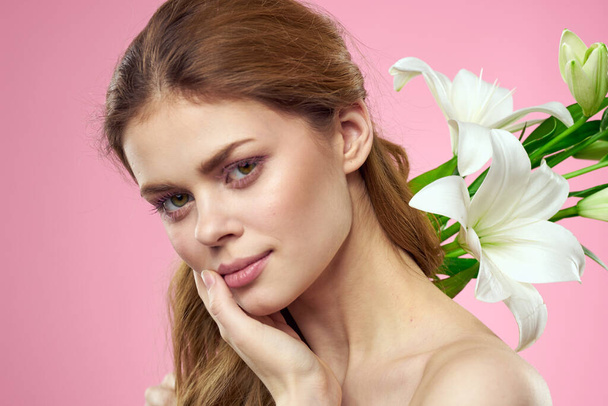 Portrait of woman with white flowers beautiful face pink background naked shoulders - Photo, Image