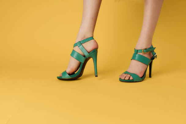 Kadınların bacakları yeşil ayakkabılar şık ayakkabılar sarı arka plan - Fotoğraf, Görsel