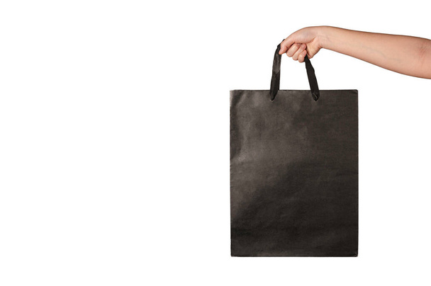 Woman hand holding shopping black paper bag isolated in white background - Photo, Image
