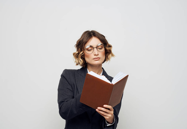 Una mujer en traje con un cuaderno en las manos sobre un modelo de trabajo de fondo claro - Foto, imagen