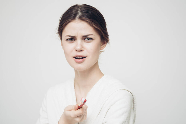 érzelmi nő egy fogkefével a kezében egy könnyű háttér és egy fehér köntös oldalnézetben - Fotó, kép