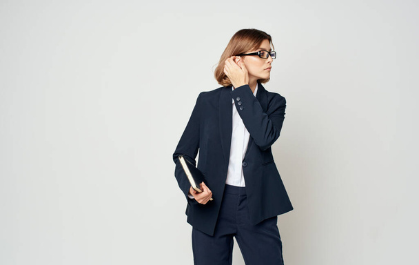 Mulher de negócios com uma jaqueta azul e uma camisa branca com óculos no rosto e um livro nas mãos - Foto, Imagem