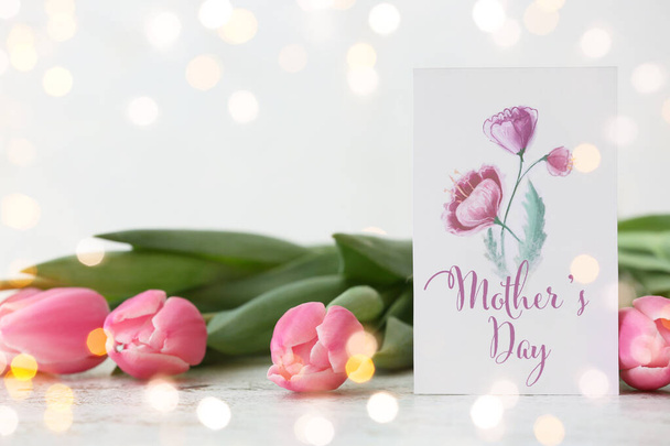 Schöne Blumen und Grußkarte zum Muttertag auf hellem Hintergrund - Foto, Bild