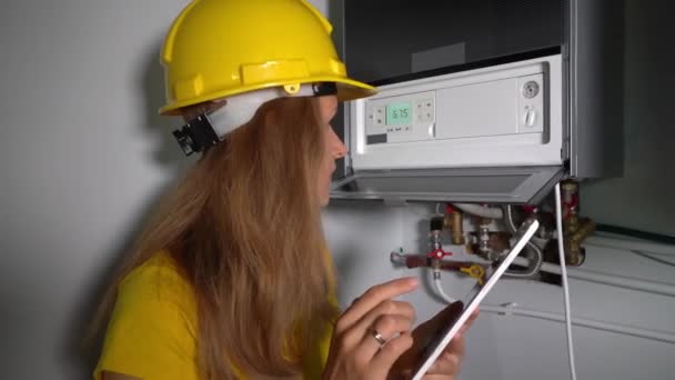 Chica técnica con tableta de la computadora inspeccionando el sistema de calefacción de la caldera de gas - Metraje, vídeo