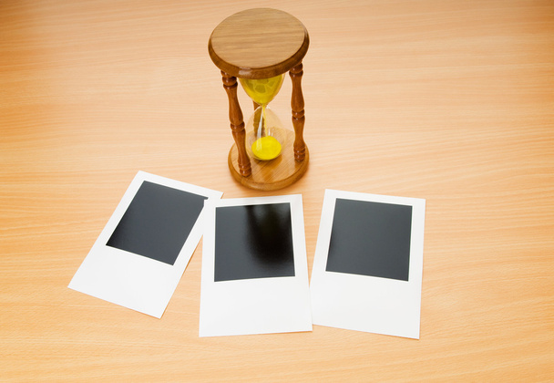 Fotos instantáneas en blanco y vidrio de hora en la mesa de madera
 - Foto, Imagen