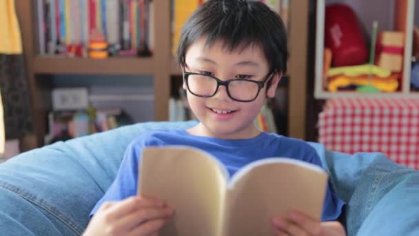 Ritratto ragazzo asiatico che legge un libro che impara lezione studio a casa, istruzione lettura concetto - Filmati, video