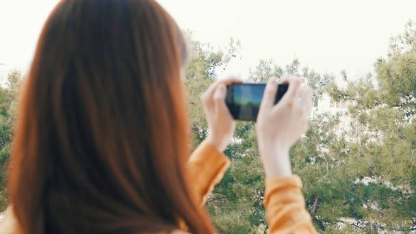 woman with phone in hands taking pictures of nature outdoors panorama - Foto, imagen