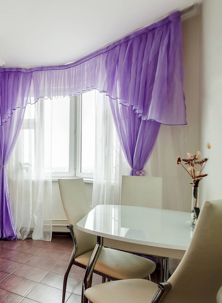 Nowoczesny przytulny dom wnętrza jadalnia z białym stołem, krzesła, fioletowe zasłony, suche kwiaty wazon - Zdjęcie, obraz