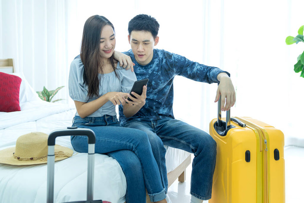 Planen Sie Urlaub Reise Urlaub. Liebespaar sucht Informationen über Handy und Buchung. Junge Asiatinnen und Asiaten bereiten sich glücklich auf die Reise vor. - Foto, Bild