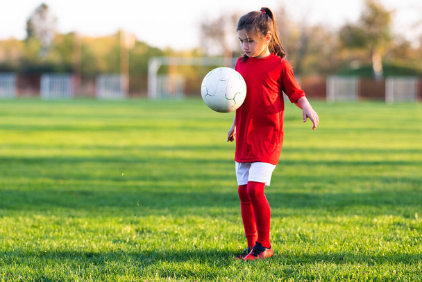 Menina chuta uma bola de futebol em um campo de futebol - Foto, Imagem