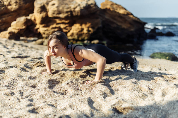Fitness fiatal nő csinál push up a strandon - Fotó, kép